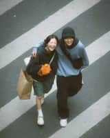 A cinematic overhead street photo of a young couple walking
