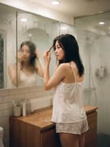 一名23歲日系女性，穿著微濕的白色細肩帶絲綢睡衣