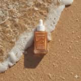 Photographie ultra-réaliste de produits de soin sur du sable de plage humide