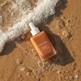 Photographie ultra-réaliste de produits de soin sur du sable de plage humide