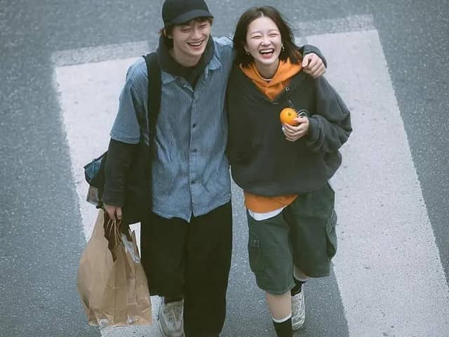 A cinematic overhead street photo of a young couple walking