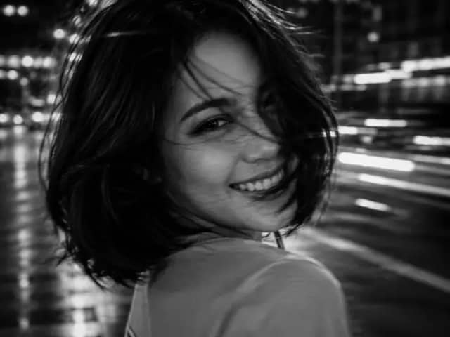 A black and white cinematic photograph of a young woman