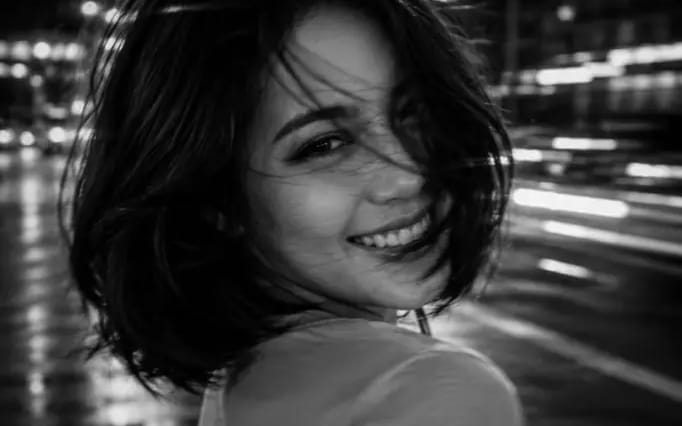 A black and white cinematic photograph of a young woman