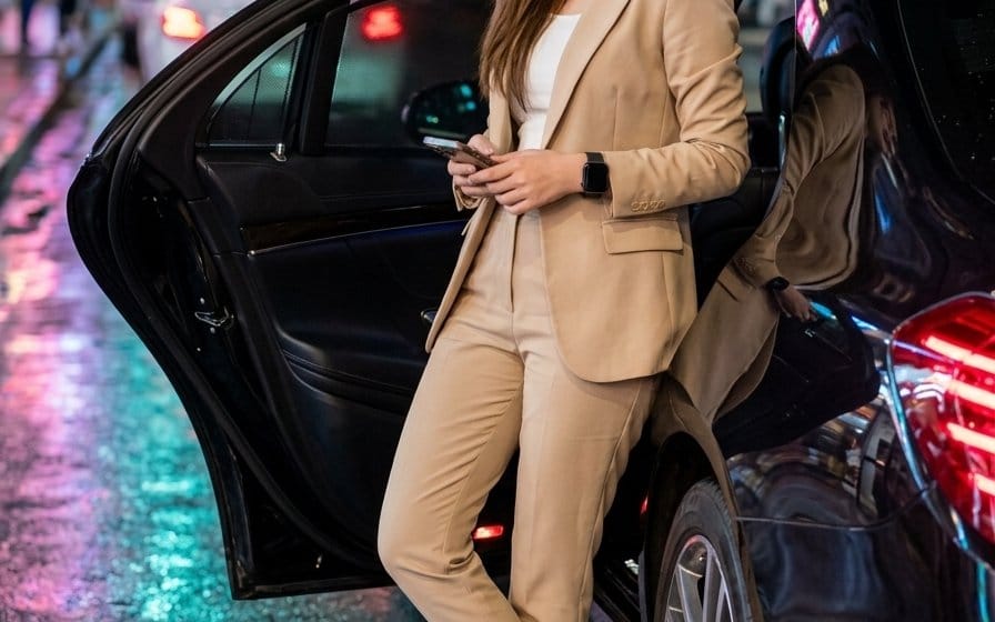 Mulher elegante com sedã de luxo à noite