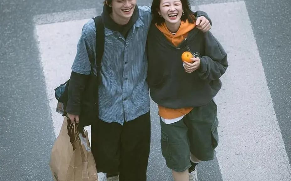 A cinematic overhead street photo of a young couple walking