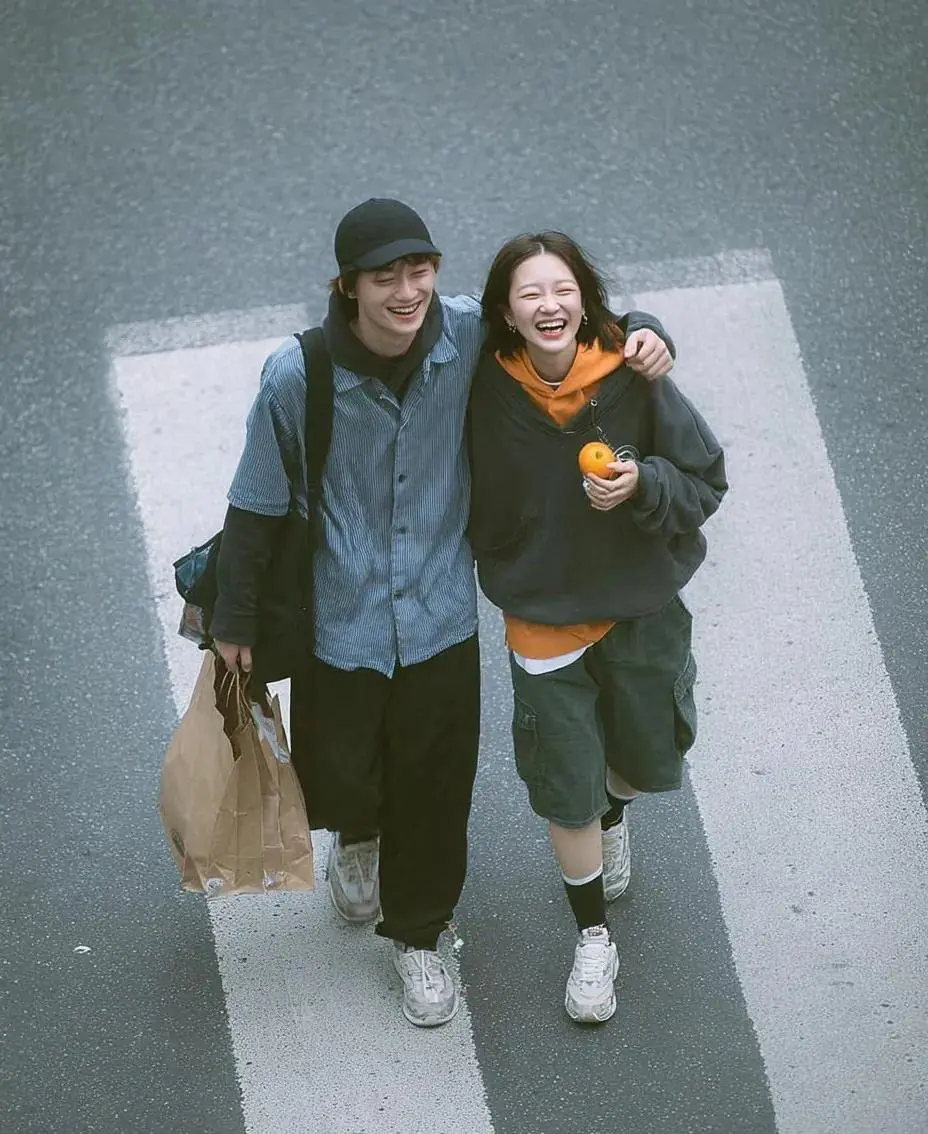 A cinematic overhead street photo of a young couple walking