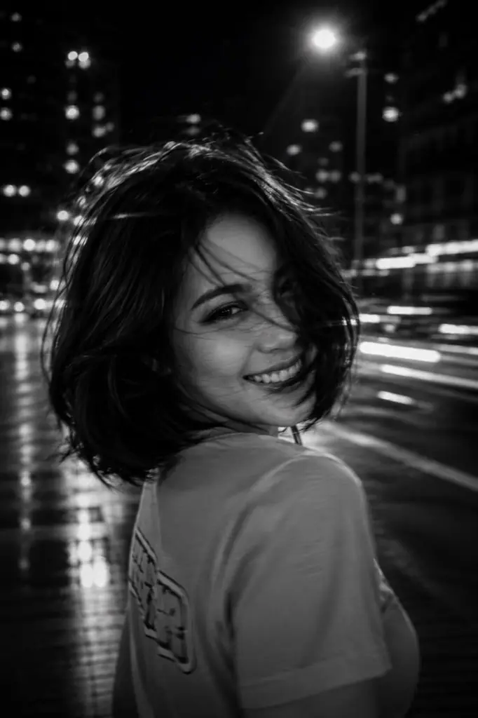 A black and white cinematic photograph of a young woman